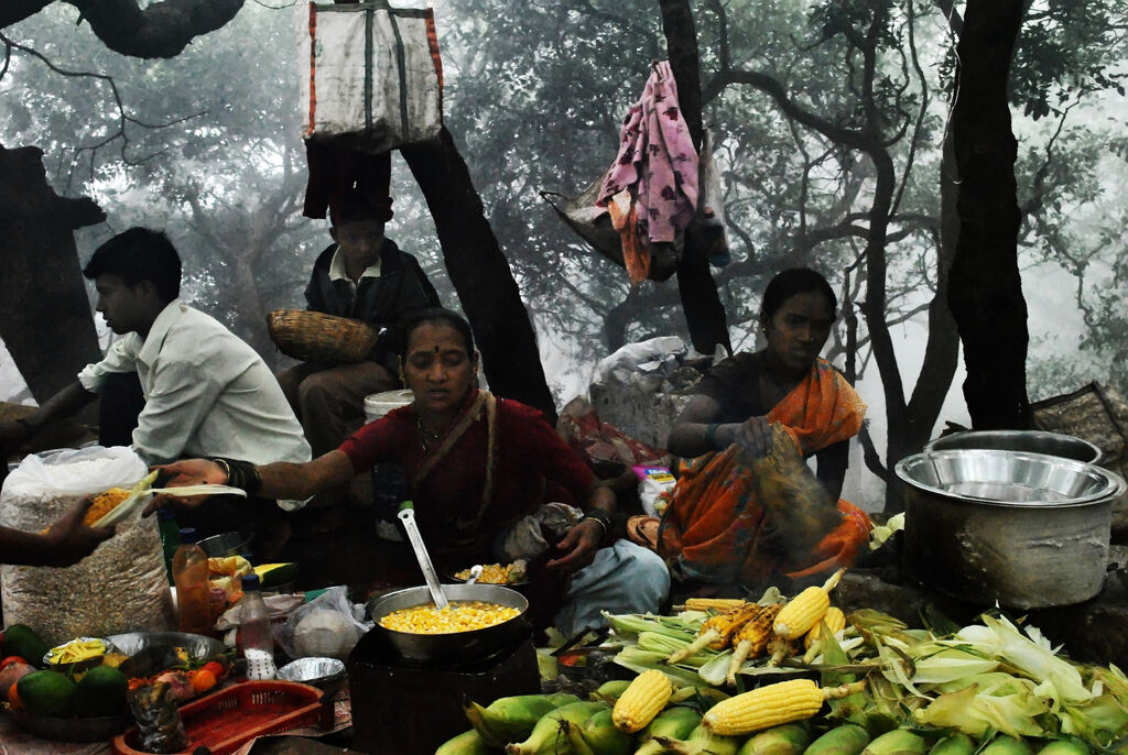 locals sell cooked corn to tourists