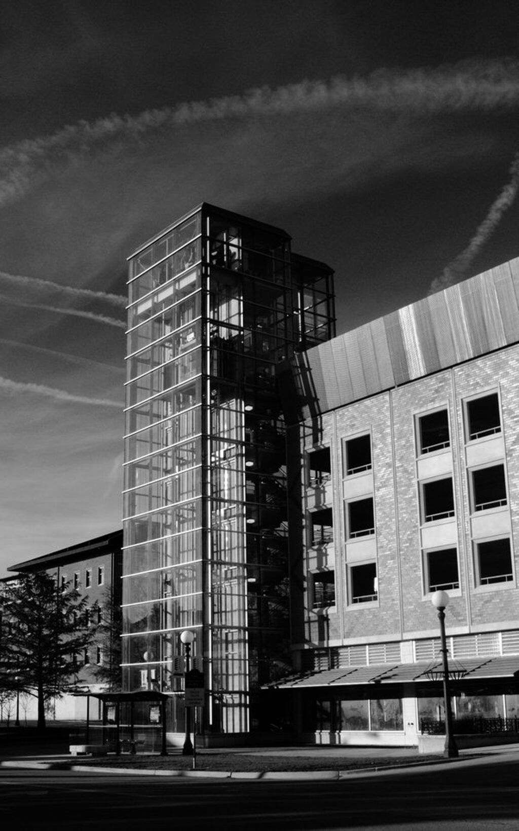 a glass and concrete building stands with cloud streaks in the sky behind